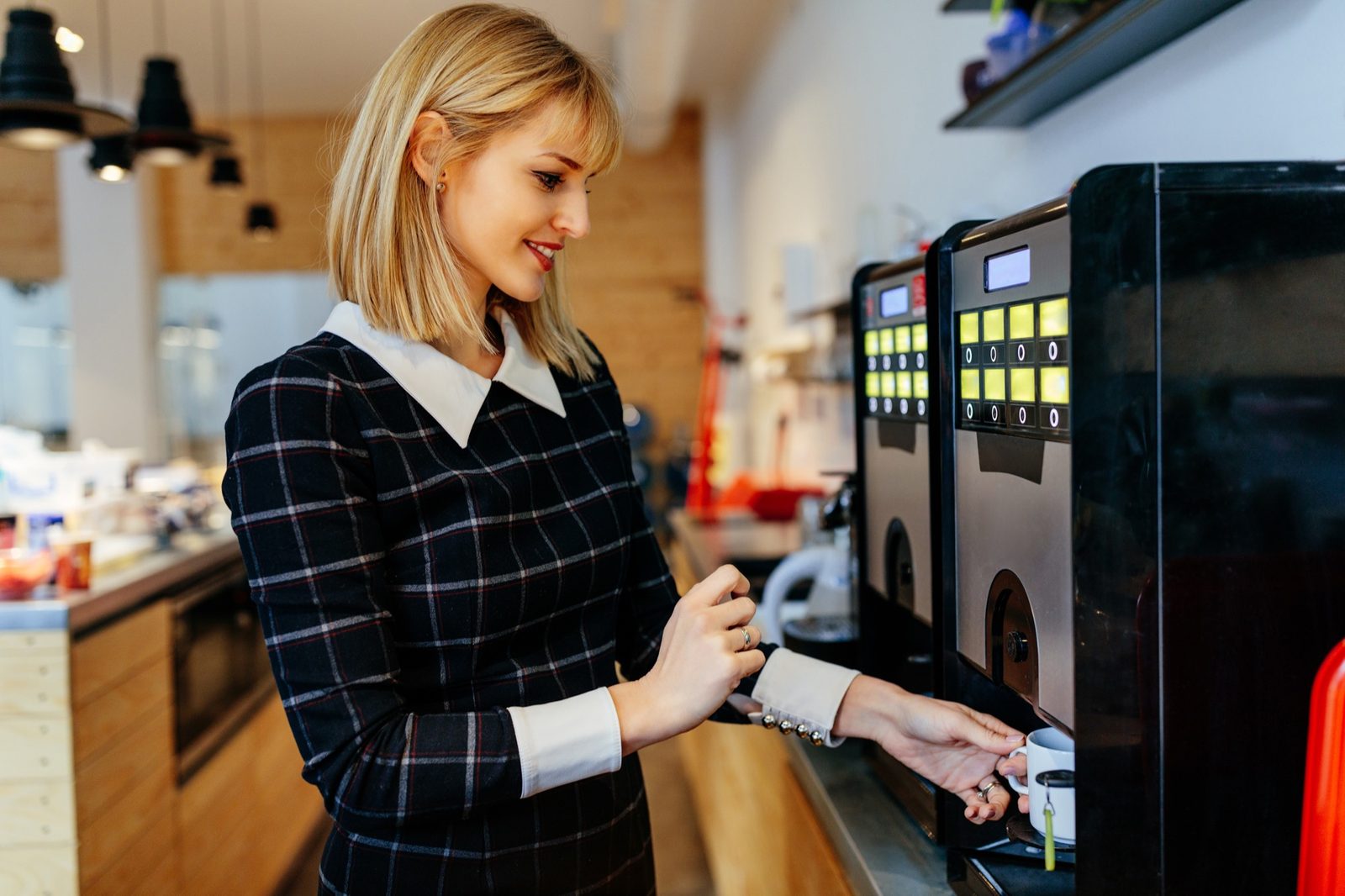 Customer drawing a fresh cup at a commercial café coffee machine