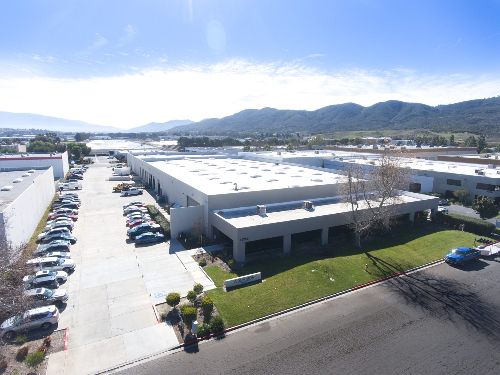 Aerial view of Aquamor's Temecula, California manufacturing facility, showing the full building footprint, employee parking, and the Aquamor ground sign