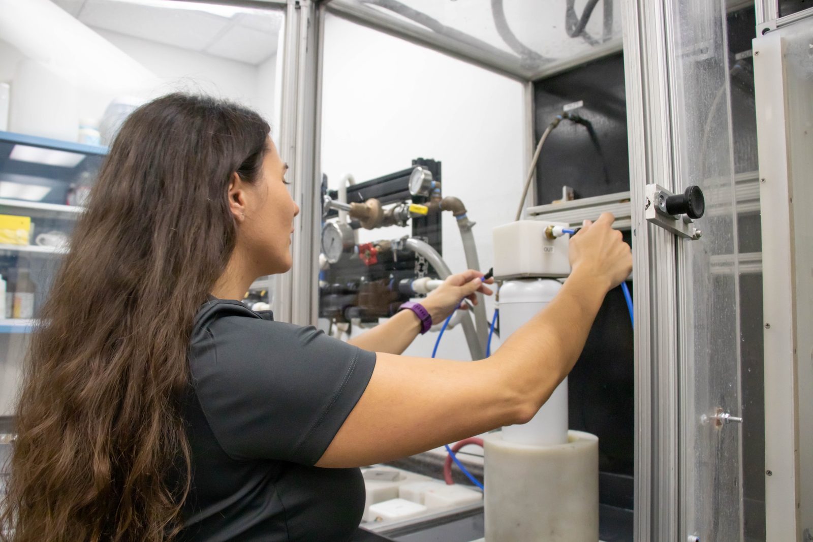Aquamor technician adjusting a test housing on the in-house lab test rig with filtration equipment and tubing
