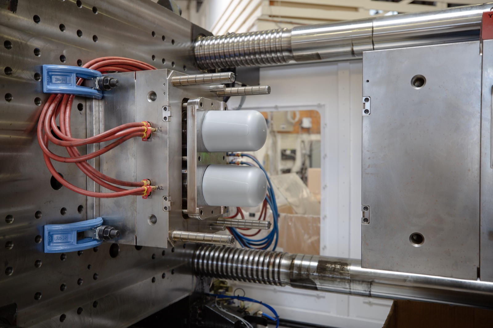 Two Aquamor filter housings mid-cycle inside an open injection mold on the Temecula production floor